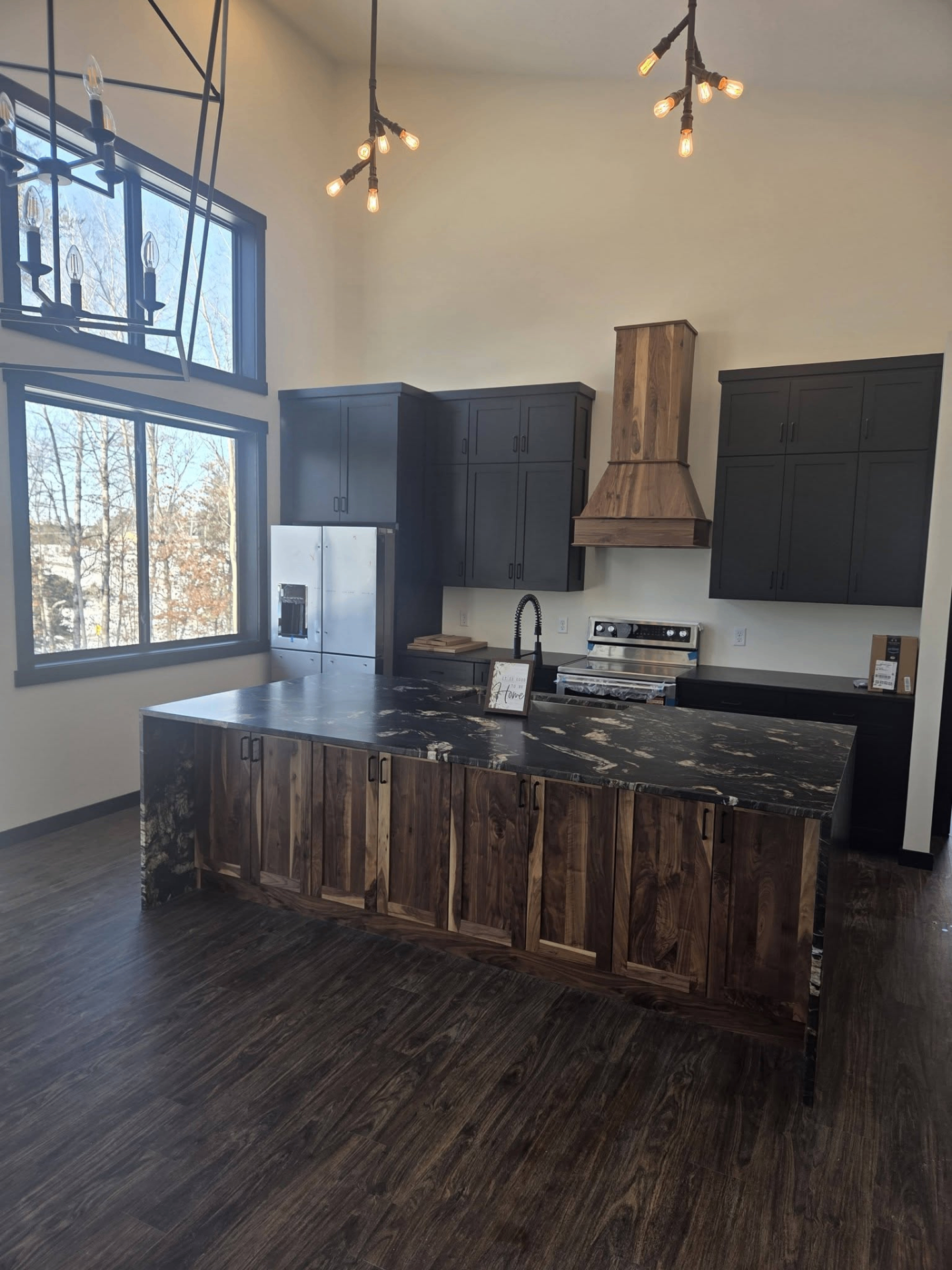 Custom kitchen with dark cabinetry, wood island, and tall ceilings